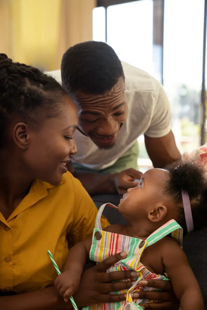 Smiling mother and father playing with their baby at home